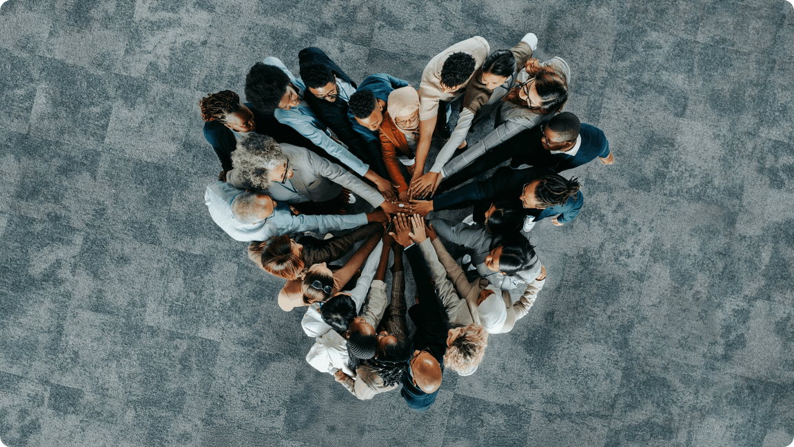 Diverse team of professionals stacking hands in a heart shape, demonstrating unity.